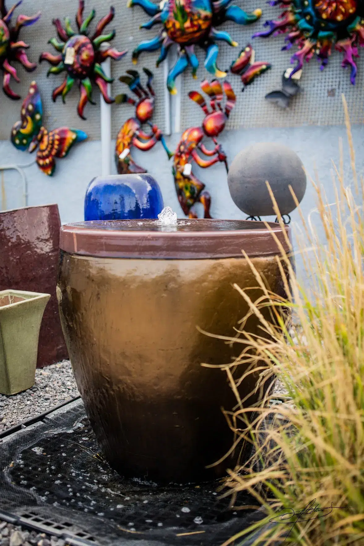 large brown pot with metal art hanging behind it
