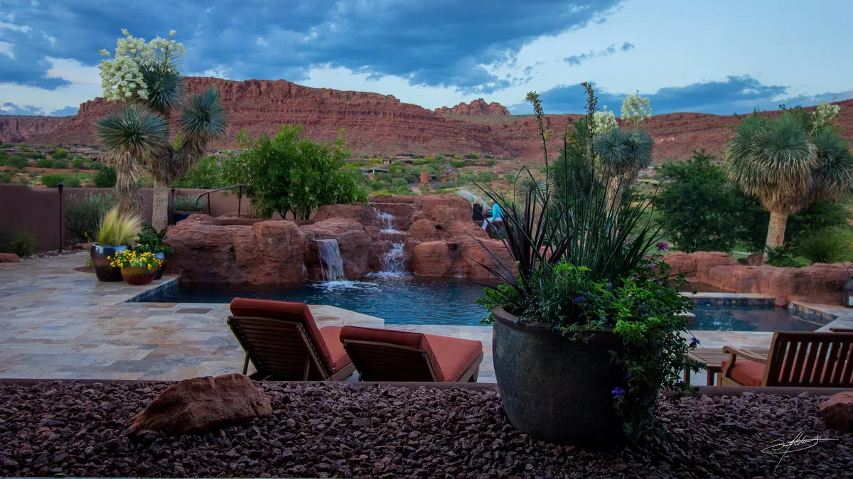 a plantscaped yard featuring a pool with a waterfall