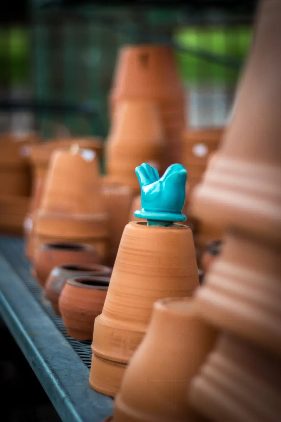 a small bluebird statue perched on a stack of terracotta pottery