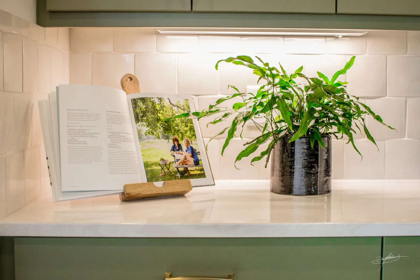 small potted plant on counter next to an open recipe book on a stand