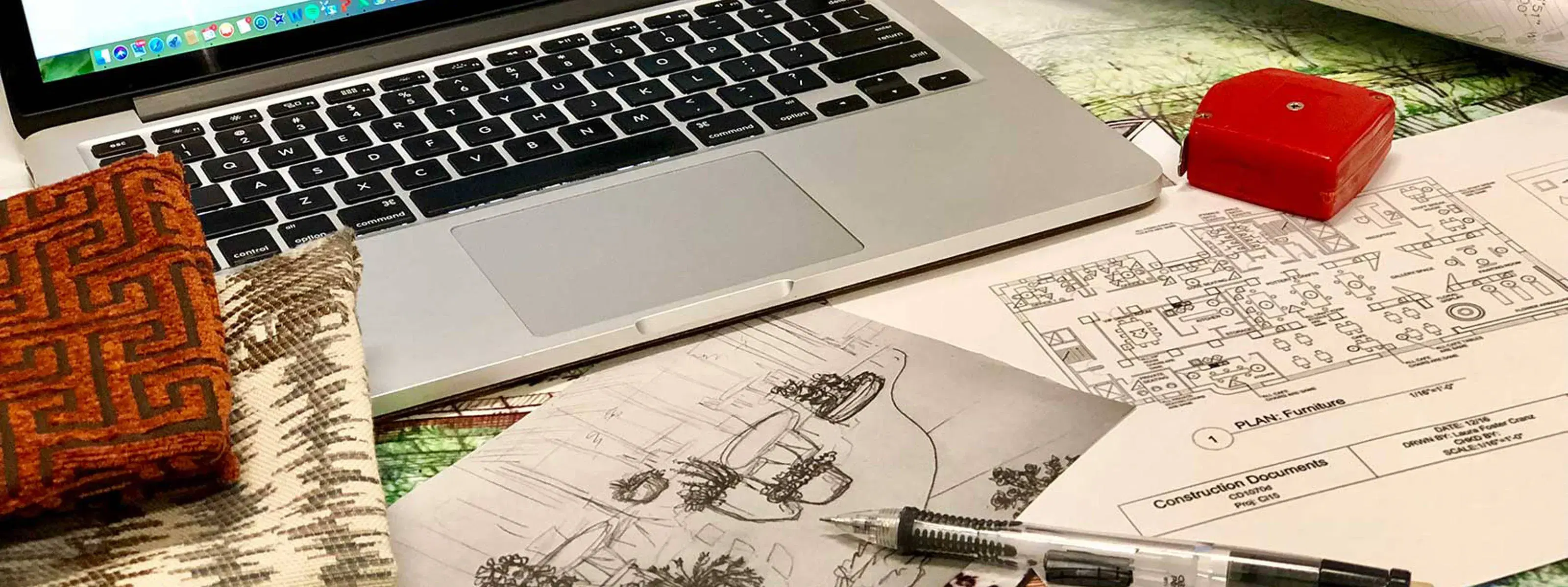laptop and measuring tape resting on top of designs and plans