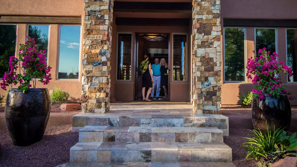 people entering the front door from a plantscaped porch
