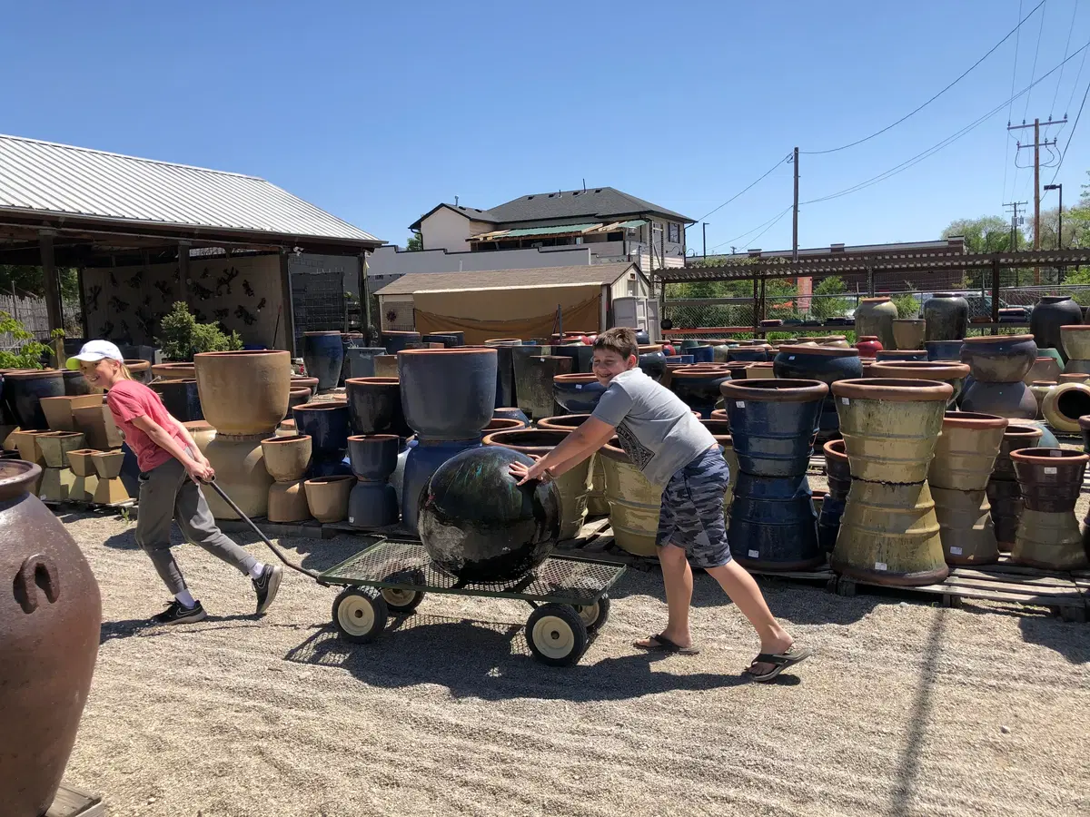 two people bringing pottery to the front of the lot