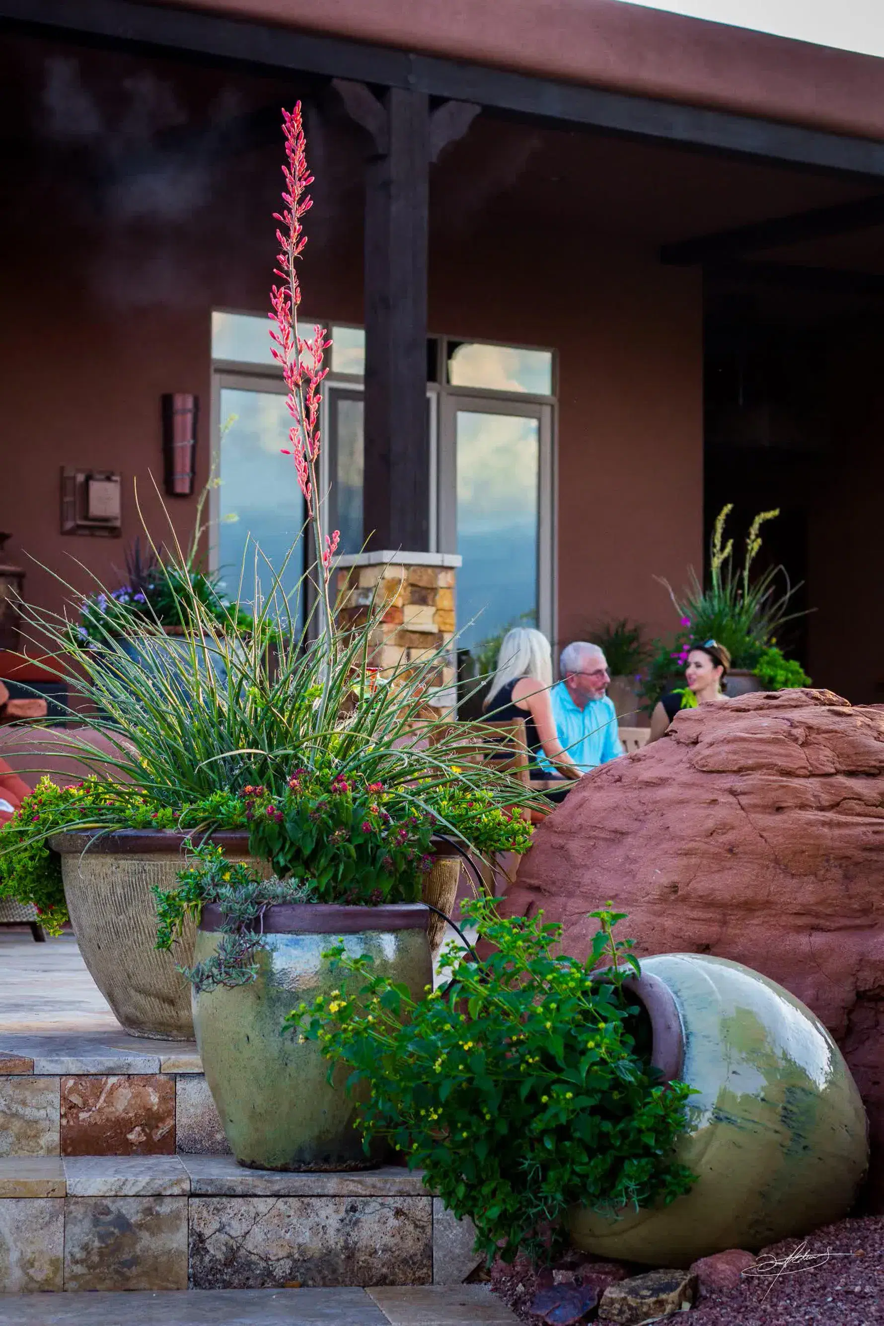 a unique outdoor pottery plantscape in front of a red rock
